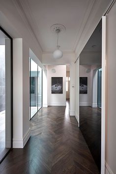 an empty hallway with wood flooring and large glass doors leading to another room in the background