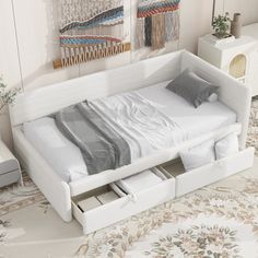 a white bed with drawers underneath it in a room filled with rugs and wall hangings