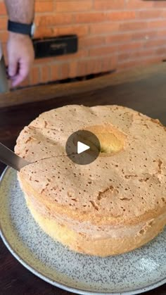 a person is cutting into a cake with a knife on a plate in front of a brick wall