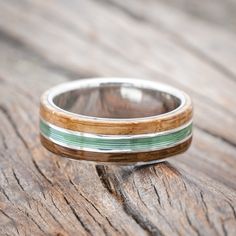 a wooden ring with green and white stripes on it sitting on a piece of wood