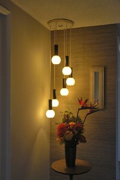 a vase filled with flowers sitting on top of a table next to a wall mounted mirror