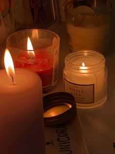 three candles sitting on top of a table next to a jar of wax and a candle holder