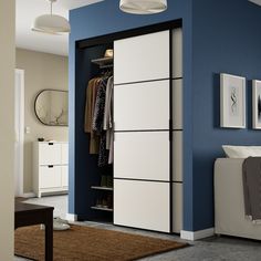 a bedroom with blue walls and white closets in it's corner, next to a bed