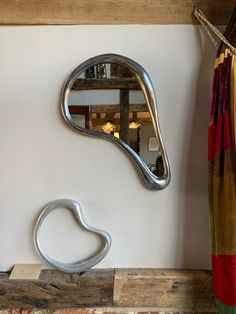 a metal object sitting on top of a wooden shelf next to a mirror and curtain