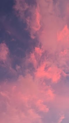 the sky is filled with pink clouds as it looks like an airplane flying in the air