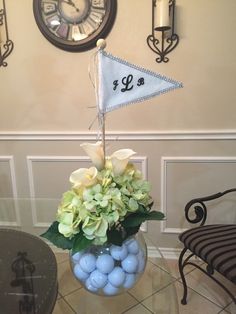 a vase filled with blue eggs and flowers on top of a table next to a clock