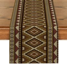 a long table runner with brown and tan designs on the top, along with a wooden floor