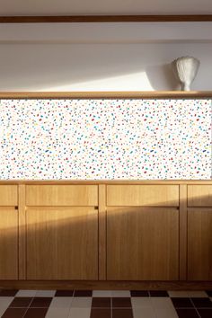 an empty room with wooden cabinets and white vases on the top shelf in front of it