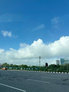 an empty highway with cars driving on it and clouds in the sky over them,