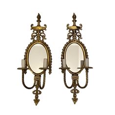 two wall sconces with candle holders and mirrors on each side, one holding a lit candle