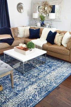 a living room filled with furniture and pillows on top of a blue rug in front of a window