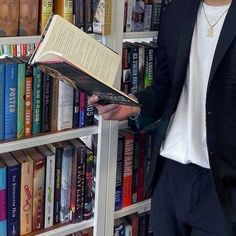 a man standing in front of a bookshelf holding a book