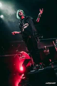 a man with green hair standing on top of a stage