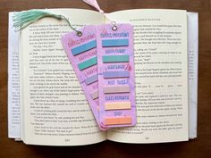 an open book with colorful sticky notes attached to the pages and a tassel hanging from it