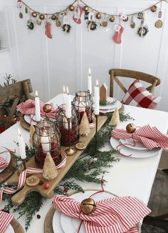 a dining room table decorated for christmas with red and white striped napkins