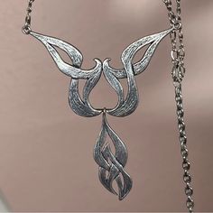 a silver necklace with two birds hanging from it's sides on a metal chain