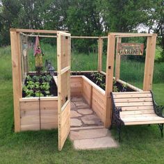 a wooden garden bench sitting on top of a lush green field with lots of plants