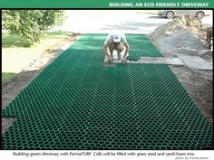 a man kneeling down on top of a green mat next to a tree and dirt road