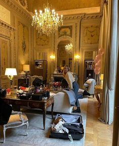 a living room filled with lots of furniture and a chandelier hanging from the ceiling