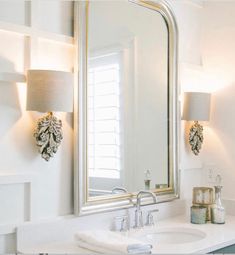 a bathroom sink sitting under a large mirror next to a light on top of a wall