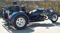 an unusual looking motorcycle is parked in front of a rock wall