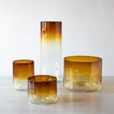 three glass vases sitting on top of a table next to each other and one is empty