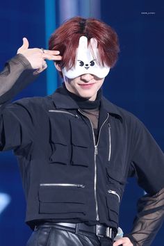 a man with red hair wearing a white mask on his face and black leather pants