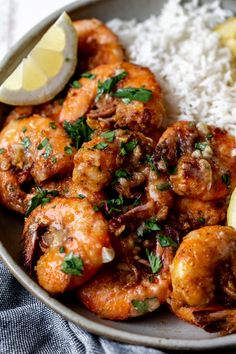 a plate full of shrimp and rice with lemon wedges on the side for garnish