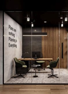 an office with glass walls and wooden flooring is pictured in this image, there are two green chairs at the desk