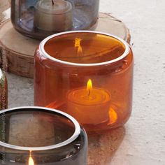 three candles sitting on top of each other in front of a jar filled with liquid