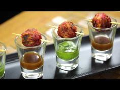 four shot glasses filled with different types of appetizers on a black serving tray