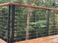 a wooden bench sitting on top of a wooden deck next to a forest filled with trees