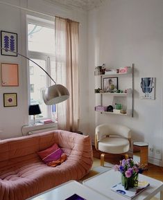 a living room filled with furniture next to a window covered in pink and white curtains