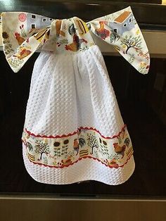 a white dress hanging from the side of a stove top with an orange bow on it