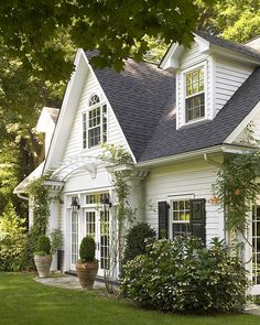 a white house with lots of windows and plants on the front lawn in front of it