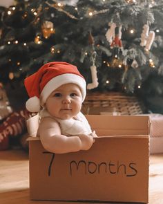 a baby wearing a santa hat sitting in a box with the number seven months written on it