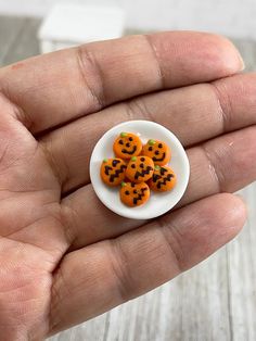 a hand holding a small white plate filled with orange buttons