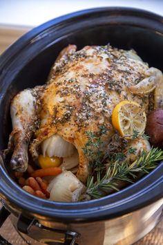 a close up of a chicken in a crock pot with potatoes and carrots