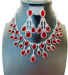 Enhance your jewelry collection with our CZ American Diamond and Red Stone Necklace set. This elegant set is perfect for any party or special occasion. The combination of CZ diamonds and red stones adds a touch of sophistication and glamour. Up your style game and stand out from the crowd with this stunning necklace set. Jewellery Care- Keep the jewellery dry, avoid contact with perfumes and water. Glamorous Red Crystal Necklaces, Red Ruby Jewelry Sets For Party, Red Rhinestone Party Necklaces, Red Rhinestone Party Jewelry, Glamorous Jewelry For Valentine's Day Formal, Glamorous Valentine's Day Jewelry For Formal Occasions, Glamorous Valentine's Day Formal Jewelry, Red Diamond Necklaces For Evening, Ruby Necklaces With Sparkling Stones For Party