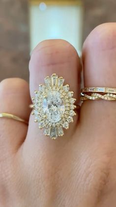 a woman's hand with two rings on it and one ring has an oval shaped diamond in the center