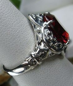 <> Made To Order This is a Gothic/Vintage revival solid sterling silver crown filigree 5ct simulated red ruby ring. The round full cut Man-made red ruby gemstone is 12mm (just shy of 1/2th of an inch) in diameter. The gemstone has great colors (greens, purples, pinks, yellow, blues, etc)... The inside of the band is marked 925 for sterling. The ring sits 18mm NS on the finger. Notice the beautiful intricate swirl design of the silver filigree setting and band. This is a lovely new, well ma Vintage Garnet Ruby Ring With Intricate Design, Vintage Red Ring For Anniversary, Classic Burgundy Jewelry For Wedding, Ornate Red Ring With Intricate Design, Vintage Red Ruby Ring With Intricate Design, Vintage Red Gemstone Jewelry, Vintage Red Filigree Ring, Antique Red Ruby Ring For Anniversary, Vintage Red Hallmarked Filigree Ring