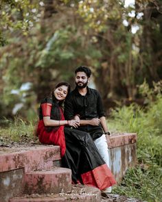 two people are sitting on some steps in the woods, one is smiling at the camera