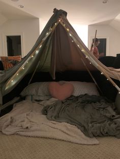 a bed that has a tent on top of it with lights hanging from the ceiling