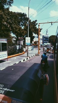 a person on a motor bike riding down the street in front of a bus stop