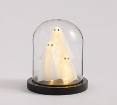 three white ghost figurines under a glass dome