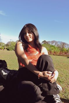 a woman sitting on the ground holding a cell phone