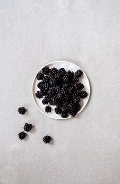 a white plate topped with blackberries on top of a table