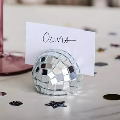 a silver disco ball sitting on top of a table next to a white sign that says ollivia