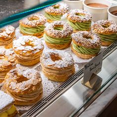 a display case filled with lots of donuts covered in powdered sugar and avocado