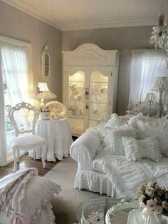 a bedroom with white furniture and chandelier in the corner, all decorated in shabby chic style